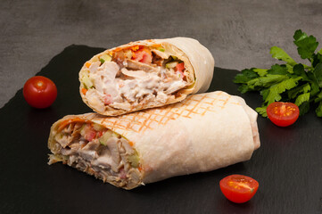 large Shawarma with vegetables and chicken on a dark background
