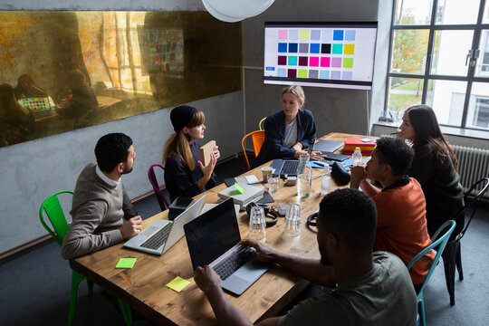 Female entrepreneur explaining strategy of product with colleagues at desk in conference room