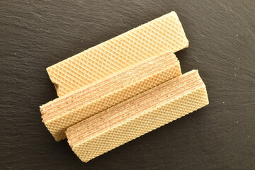 Three fragrant vanilla waffles, close-up, on a slate board, top view.