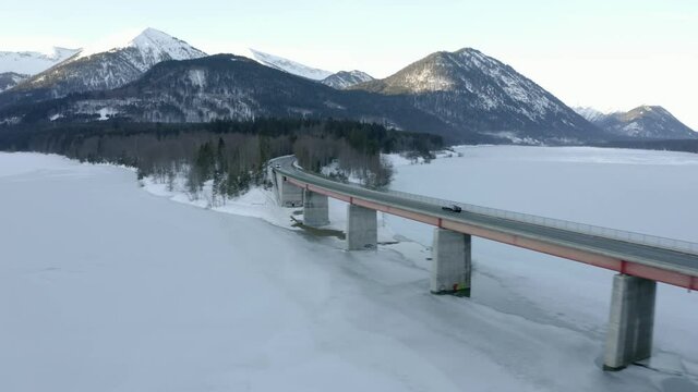Car driving over beautiful bridge in stunning scenery landscape in bavaria during winter, aerial view.