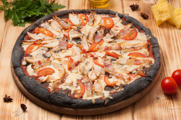 pizza with chicken and bacon on black dough