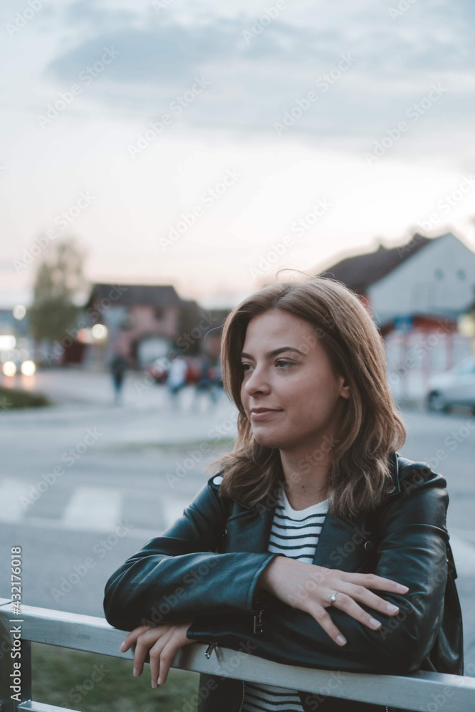 Poster vertical shot of a blonde female in a leather jacket outdoor