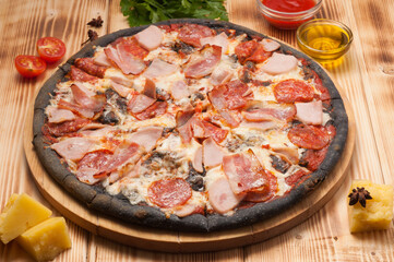 pizza with pepperoni ham and bacon on black dough