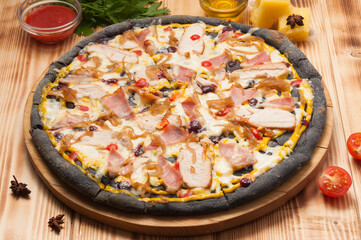 pizza with chicken bacon and onions on black dough