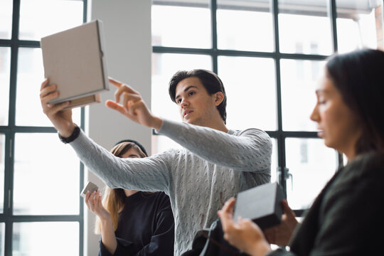 Male entrepreneur explaining about product to female colleagues in creative office