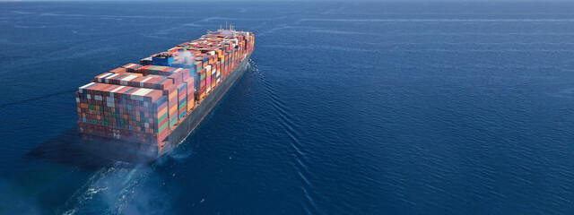 Aerial drone ultra wide photo above huge colourful container carrier vessel cruising deep blue open...