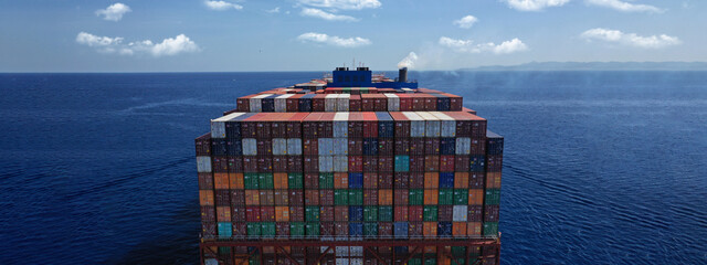 Aerial drone ultra wide photo above huge colourful container carrier vessel cruising deep blue open...