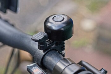 one black bicycle bell on the metal handlebar of a sports bike on the street