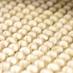 Uncooked raw ravioli or Dumplings. Group of identical objects. Soft focus. Background or texture. Rows of raw dough dish sprinkled with flour. Preparation of Convenience Food. Square format 1x1.