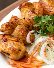 Pieces of Baked chicken meat with salad on white plate. Hearty meat lunch or dinner. Close up shot, soft focus. Vertical format for banner.