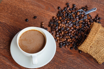 cup of coffee and coffee beans in a sack on  Brown background, top view