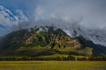Russia. South of Western Siberia, Mountain Altai. Morning fog on the mountain tops in the valley of...
