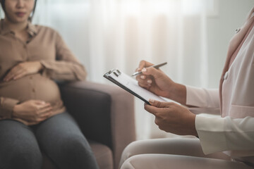 Panic, Stress asian young pregnant woman holding belly, abdomen while gynecologist consult symptoms of pregnancy unborn child of mom. Health care medical, protection, prenatal at clinic, hospital.