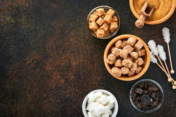 White sugar, cane sugar cubes, caramel in bamboo bowl on dark brown table concrete background. Assorted different types of sugar. Top view or flat lay.