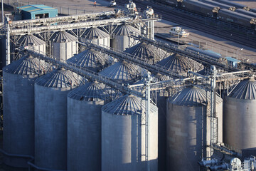 Aerial photograph taken from a helicopter of large industrial storage silos at a British port. A freight train can be seen behind the huge vertical metal tanks. © Tom Falcon Harding 