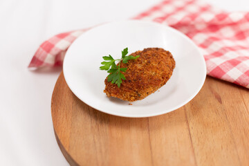 Poultry cutlet decorated with parsley on a white background
