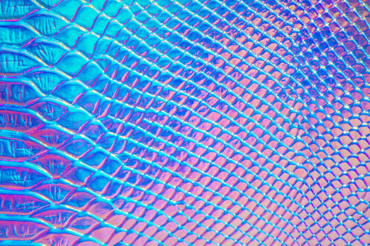 Abstract background with holographic bright rainbow multicolor. Metallized macro close up. Imitation of rainbow color. Background with a reptile skin texture in pink and blue toned