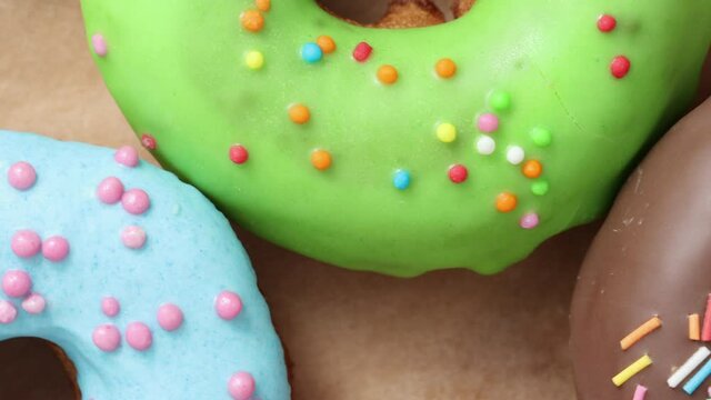 Rotating shot of tasty sweet colorful donuts with icing and sprinkles, close-up and macro 4k video.