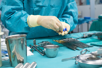 Fototapeta na wymiar Medical team performing operation. Close up of scrub nurse taking medical instruments for operation. Medical and instrumentalist nurse working in an operating room with scissors of surgery.