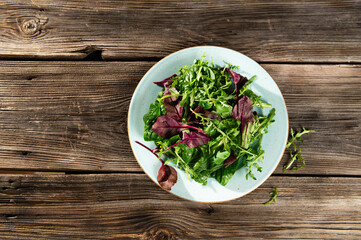 salad mix of fresh herbs, arugula, Swiss chard, spinach in tarenle on a wooden background, serhu view
