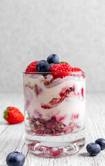Muesli with yogurt and berries in a glass On a wooden table. Dessert preparation process. Fitness food. Copy space. High quality photo