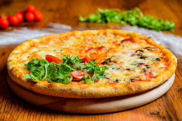 Italian pizza with cheese tomatoes, arugula and mushrooms on wooden cutting board stock photo.