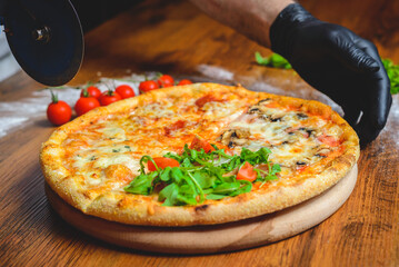 Close up of a chef in gloves slicing pizza on the cutting board