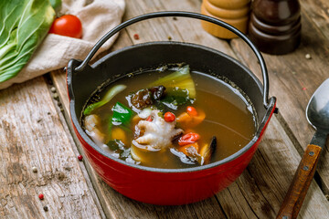 Chinese Seafood Soup in a cast-iron pot on old wooden table