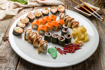 set of sushi  rolls on white plate on old wooden table