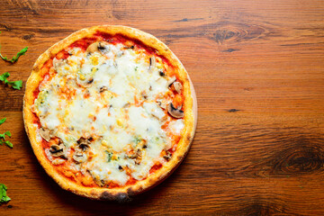 Italian pizza with cheese tomatoes, arugula and mushrooms on wooden cutting board stock photo.
