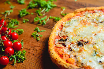 Italian pizza with cheese tomatoes, arugula and mushrooms on wooden cutting board stock photo.