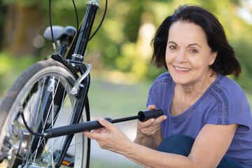 Obraz premium senior woman inflates bicycle tyre