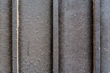 Metal wall with three pillars covered with black paint. Close up view