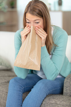 blond woman holding a brown paper bag over mouth