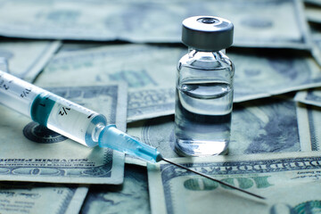 Vaccine vial and syringe on the background of one hundred dollar bills