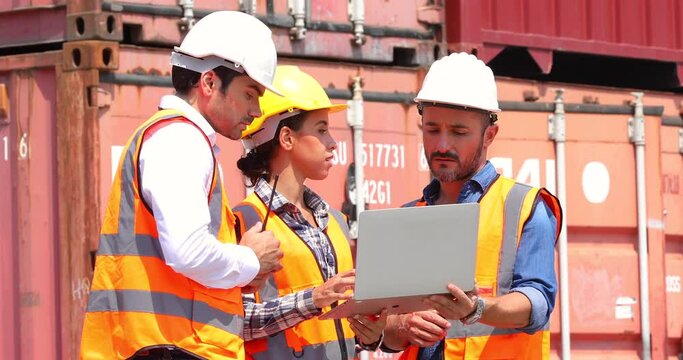Hispanic man harbor worker talking on the walkie-talkie radio and control loading containers at container warehouse. container yard port of import and export goods