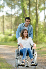 couple at wheelchair walk through the forest