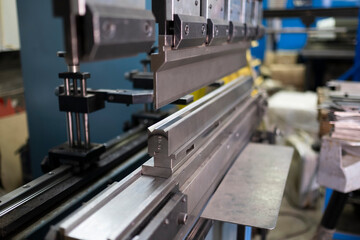 Bending sheet metal with a hydraulic machine at the factory, operator bending metal sheet by sheet...