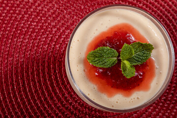 Lemon mousse in crystal bowl with strawberry jelly topping and mint