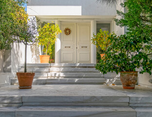 elegant white house facade and entrance door with potted plants, Athens Greece