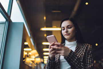 Focused woman messaging via smartphone in coffee shop