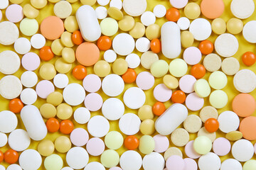 Many colored tablets of different shapes on a yellow background.