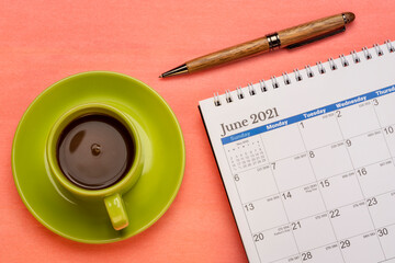June 2021 - spiral desktop calendar with a pen and cup of coffee flat lay, time and business concept