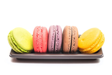 Pastel colorful many macarons with different flavors on plastic tray isolated on white background....