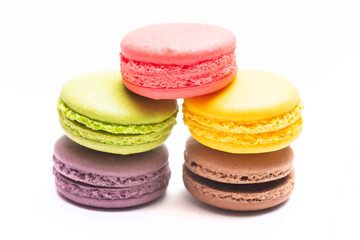 Various flavors of pastel macarons stacked against isolated on white background. Macarons is a delicate meringue-based cookie sandwich It is a dessert of French origin.