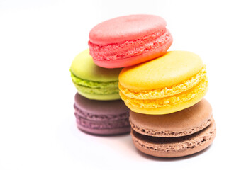 Various flavors of pastel macarons stacked against isolated on white background. Macarons is a delicate meringue-based cookie sandwich It is a dessert of French origin.