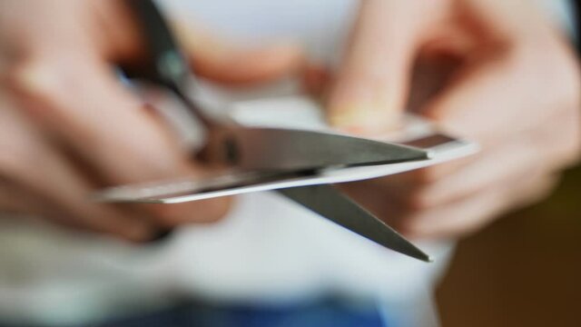 Woman cuts credit card with scissors.