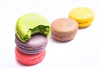 Bitten macaron and Various flavors of pastel macarons stacked against isolated on white background....