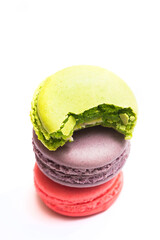 Bitten macaron and Various flavors of pastel macarons stacked against isolated on white background....