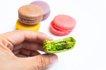 Bitten macaron and Various flavors of pastel macarons stacked against isolated on white background....